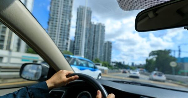 Driver traveling along an urban road near high-rise buildings, representing convenient access to key destinations and major city routes