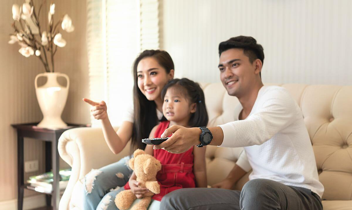 Parents and their young daughter relaxing together on a sofa in a bright condominium living room