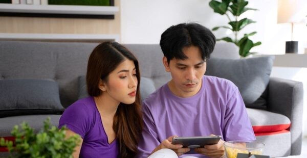Couple reviewing property information together with a tablet, documents, and a model house in a modern living room