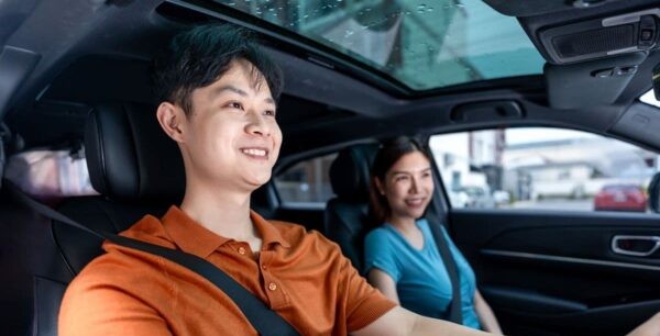 Young couple driving together through the city, representing the convenience and accessibility of urban condominium living