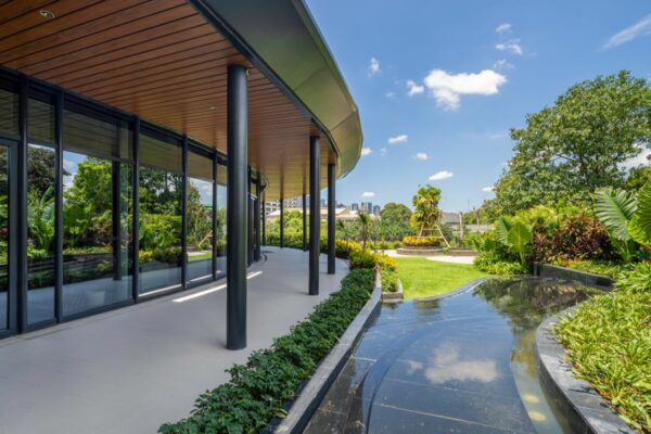 Landscaped residential walkway beside floor-to-ceiling glass windows, reflecting how thoughtful architecture connects indoor spaces with surrounding views