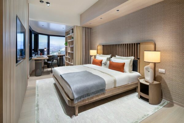 Modern condominium bedroom with a spacious bed, bedside lamps, and a separate work area near the window