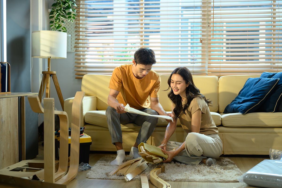Couple unpacking together in a bright condominium living room with comfortable seating and large windows