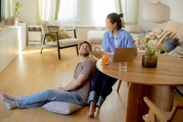 Couple relaxing together in a modern condominium while reviewing information on a laptop